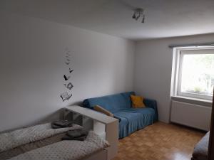 a living room with a blue couch and a window at Starling Loka in Škofja Loka