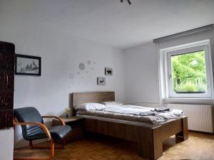 a bedroom with a bed and a chair and a window at Starling Loka in Škofja Loka