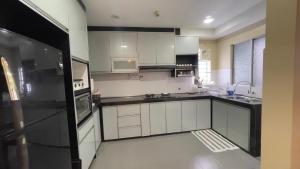 cocina con armarios blancos y nevera negra en Cozy Homestay Putrajaya, en Putrajaya