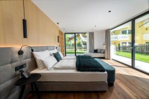 een slaapkamer met een groot bed en een groot raam bij Anna Lodges Dolomites in Santa Cristina in Val Gardena