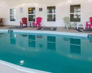 - une piscine avec des chaises, des tables et des chaises rouges dans l'établissement Quality Inn, à Moncton