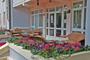 einen Balkon mit Stühlen und Blumen auf einem Gebäude in der Unterkunft Hotel Prezident in Palić