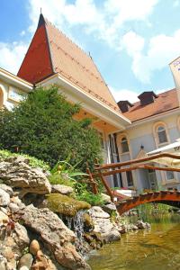 ein Haus mit einer Brücke über einen Wasserlauf in der Unterkunft Hotel Prezident in Palić