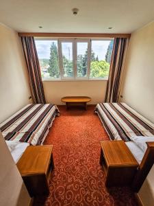 a room with two beds and a table and a window at Garni Hotel BaMBiS in Podgorica