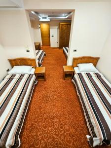 a row of three beds in a room at Garni Hotel BaMBiS in Podgorica