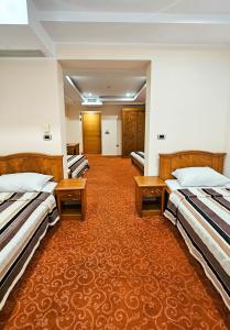 three beds in a hotel room with orange carpet at Garni Hotel BaMBiS in Podgorica