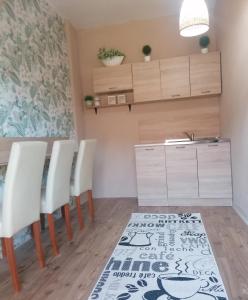 a kitchen with white chairs and a table and a rug at Apartman ClaRa in Štúrovo