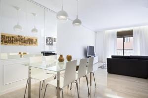 una sala da pranzo con tavolo in vetro e sedie bianche di Stay U-nique House Torre Damians a Barcellona