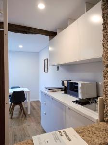 a kitchen with white cabinets and a table with a chair at DOMI Suites & Studios in Guimarães