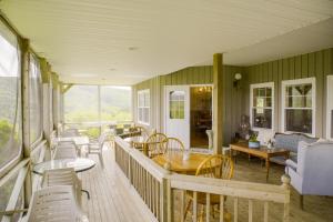 een overdekte veranda met tafels en stoelen en een bank bij Chanterelle Inn & cottages in Baddeck