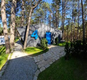 a small house with a blue door in the woods at FLY House Łeba in Łeba