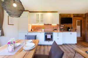 cocina con armarios blancos y mesa de madera en Appartement Auszeit, en Alpbach