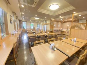 une salle à manger avec des tables et des chaises en bois dans l'établissement Hotel Route-Inn Hon Hachinohe Ekimae, à Hachinohe