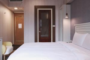 una camera da letto con un grande letto bianco e una porta di Kindness Hotel Taitung Branch a Città di Taitung