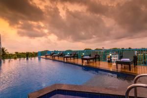 a swimming pool with chairs on a resort at De Mandarin Goa in Candolim