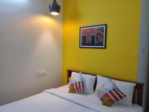 - une chambre dotée d'un lit avec un mur jaune dans l'établissement FULL moon, à Cochin