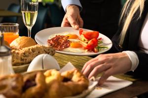 uma pessoa sentada numa mesa com um prato de comida para o pequeno-almoço em Akadémia Hotel em Balatonfüred