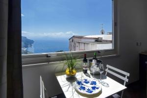 una mesa con 2 botellas de vino y una ventana en La Moresca, en Ravello