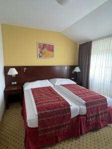 a hotel room with a large bed with a red blanket at Wellness Hotel Svachovka in Český Krumlov