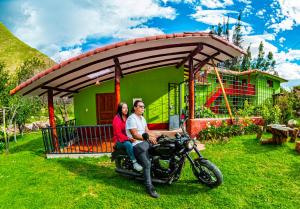 een man en vrouw op een motor voor een huis bij Happy Land Valle Sagrado in Urubamba