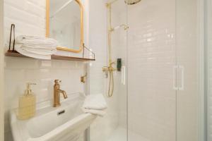 baño blanco con ducha y lavamanos en L'Appartement d'Amélie, en Nancy