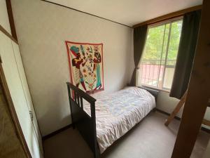 una piccola camera con letto e finestra di Guesthouse Oomiya base 大宮基地別荘 a Chiba