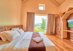 een slaapkamer met een groot bed en een groot raam bij AJ Gable Clouds Ooty by VOYE HOMES - Serene Stay Near Avalanche Emerald Lake in Ooty