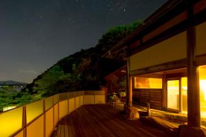 une maison avec une terrasse en bois la nuit dans l'établissement Sennenmatsu, à Imabari