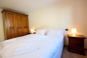 a bedroom with a large white bed with two lamps at Residence La Corte in Vezza dʼOglio