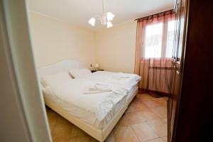 a bedroom with a white bed and a window at Residence La Corte in Vezza dʼOglio