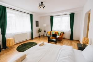 1 dormitorio con cama blanca y cortinas verdes en Apartamenty Krzywa, en Krosno