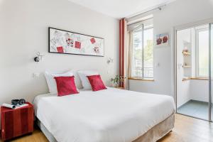 een slaapkamer met een groot wit bed met rode kussens bij Villa Elisa M in Aubenas