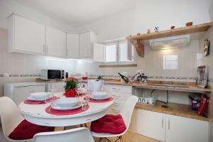 una cocina blanca con una mesa con sillas acolchadas de color rojo en Páteo da Várzea 4, en Colares