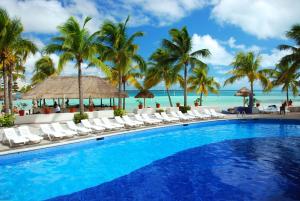 una piscina con sedie e palme sulla spiaggia di Grand Oasis Palm - All inclusive a Cancún