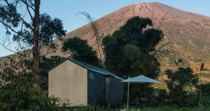 a shed with an umbrella in front of a mountain at Bobocabin Gunung Rinjani, Lombok in Sembalun Lawang