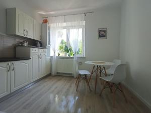 een keuken met witte kasten en een tafel en stoelen bij relax apartament in Skarżysko-Kamienna