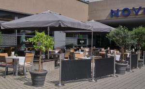 um restaurante com mesas e guarda-sóis em frente a um edifício em Novotel München City em Munique