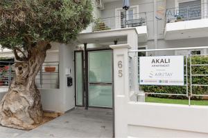 un arbre devant un bâtiment avec un panneau dans l'établissement Akali Apartment airport by Airstay, à Spáta