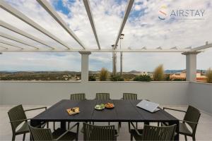 d'une terrasse avec une table, des chaises et un ordinateur portable. dans l'établissement Akali Apartment airport by Airstay, à Spáta