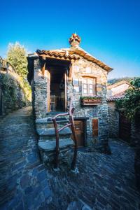 une maison en pierre avec une statue en face de celle-ci dans l'établissement Montanhas do Xisto - Casa do Portal, à Lousã