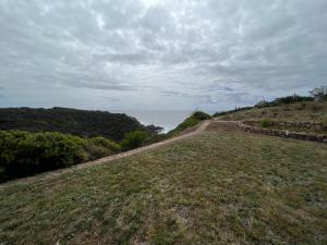 a dirt road next to the ocean on a hill at Monte novo in Odeceixe