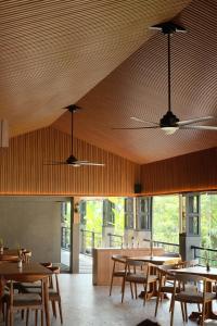 un restaurant avec des plafonds en bois, des tables et des fenêtres dans l'établissement Citrus-House com Hotel, à Bogor