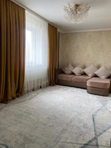 salon z kanapą i oknem w obiekcie Apartment Plaza w mieście Szymkent