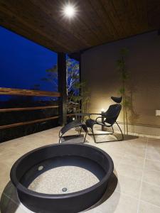 een hot tub in een kamer met 2 stoelen en een tafel bij 宮島離れの宿 IBUKU 別邸 -Miyajima Hanarenoyado IBUKU Bettei- in Ōno