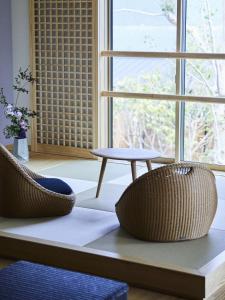 twee stoelen en een tafel voor een raam bij 宮島離れの宿 IBUKU 別邸 -Miyajima Hanarenoyado IBUKU Bettei- in Ōno