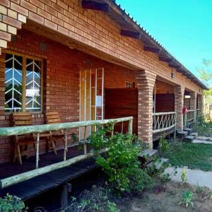 a brick house with a wooden porch and a balcony at Sunshinevibe guest house in Kasane