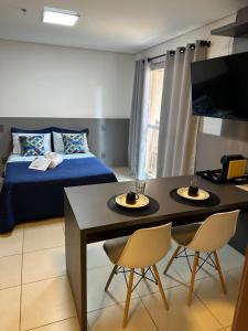 een slaapkamer met een bed en een tafel en stoelen bij Studio 303 - Extraordinário in Ribeirão Preto