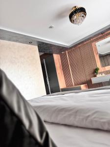 una camera con letto bianco e lampadario pendente di Hanul Domnesc Imperial Hotel & SPA a Călan