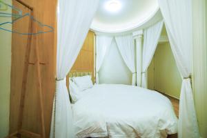 a bedroom with a white bed with curtains at Zhangjiajie Han Exotic Inn in Zhangjiajie