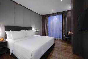 1 dormitorio con 1 cama blanca grande y TV en Harper Premier Nagoya Batam, en Nagoya